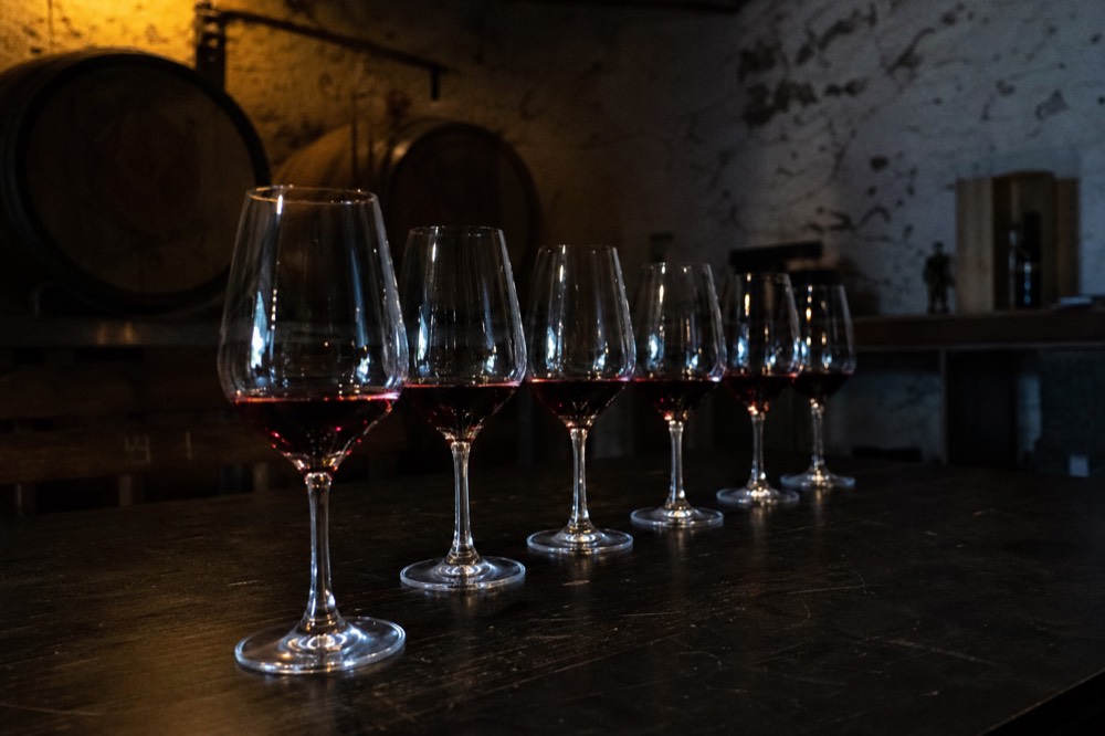 A reserve tasting flight of aged red wines in stemware on a dark cellar table, moody low light, no text, no logos, no people