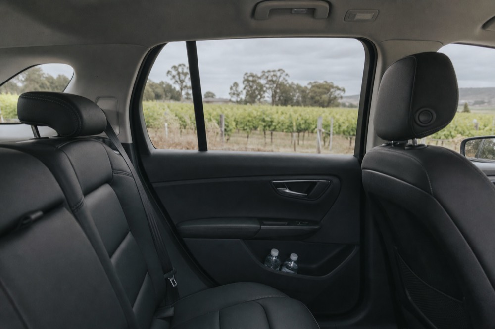 Interior of a clean SUV with bottled water and vineyard views through the windows, soft daylight, no text, no logos, no people